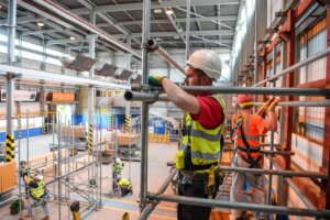 Construction workers assembling scaffolding indoors