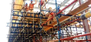 Construction workers wearing safety gear working on elevated scaffolding during a building project.