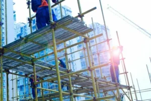 Workers assembling yellow scaffolding on building site