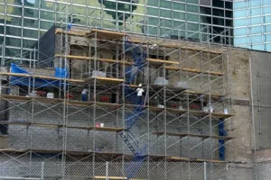 Building facade under construction with extensive scaffolding and workers.
